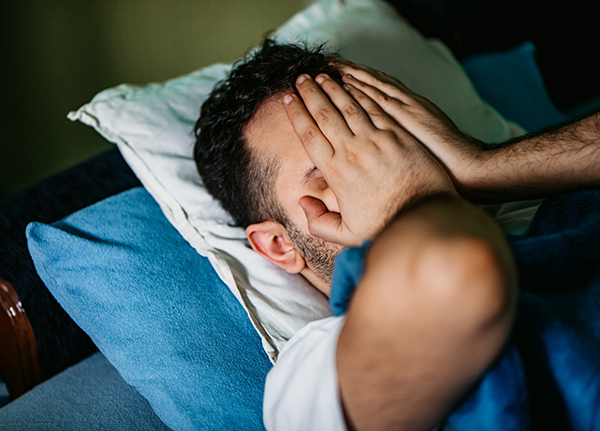 Man in bed covering face