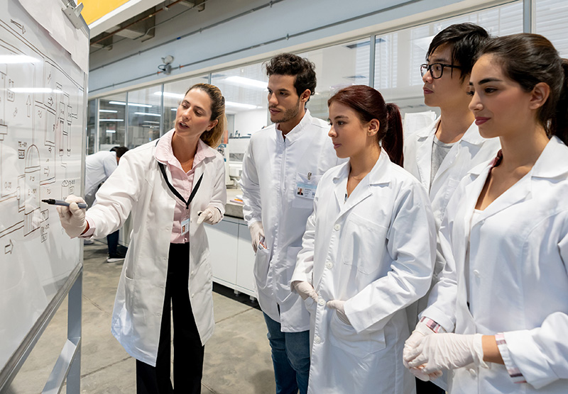 Students and teacher in lab coats looking at something