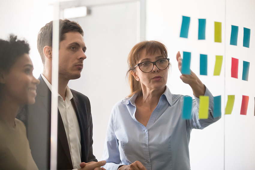 A group of people looking at sticky notes on a board