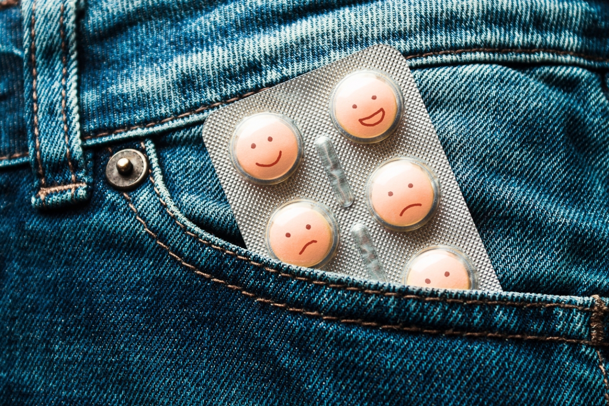 A blister card of pills with faces drawn on them in a jean pocket