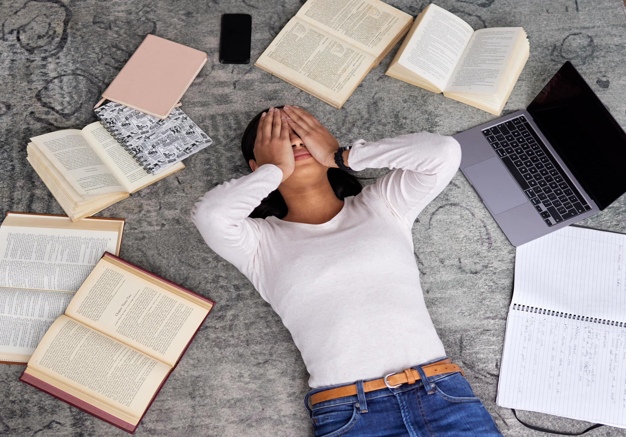 Woman surrounded by study materials looking overwhelmed