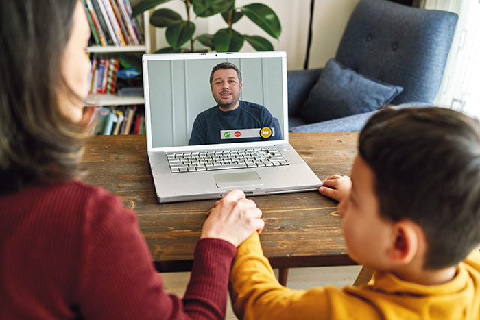 Mother and son in front of laptop talking to man