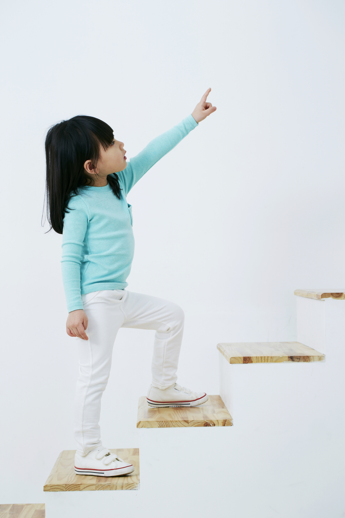 A child climbing the stairs and pointing ahead