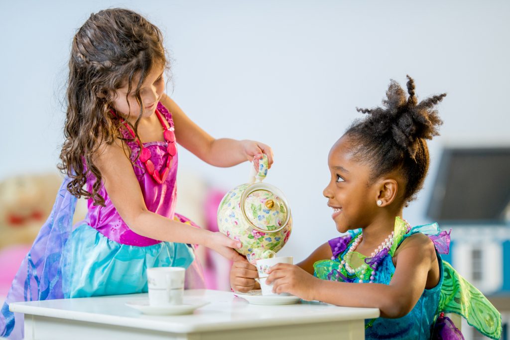 two little girls in dress ip costumes having a tea party