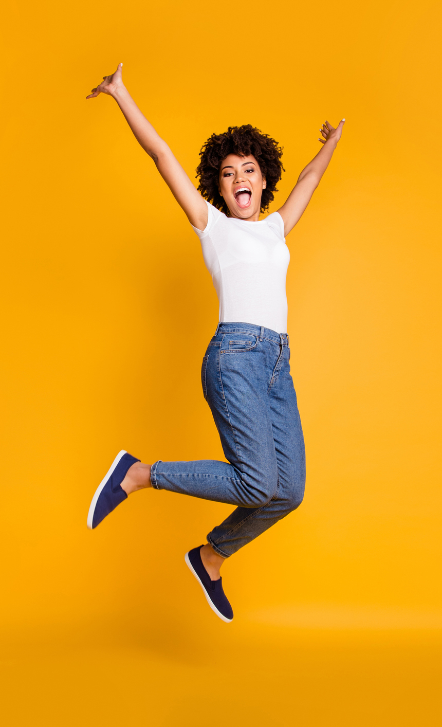 Woman "jumping for joy" on a bright yellow background