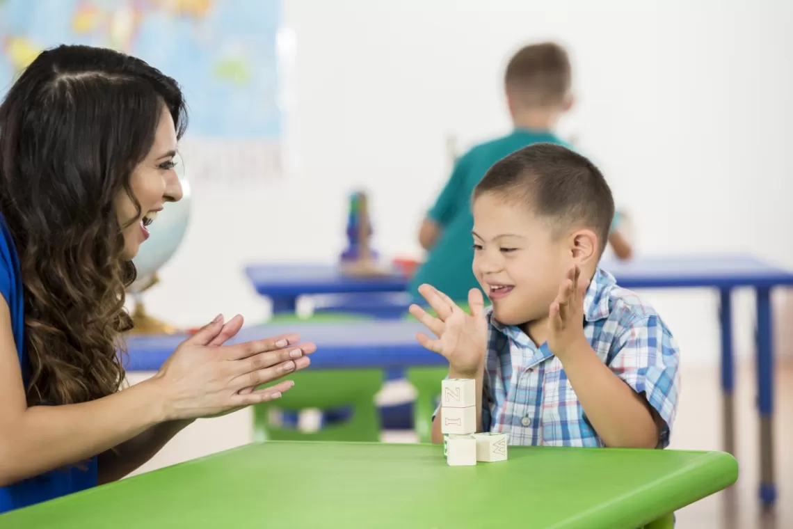 Teacher and young student clapping in a classroom 