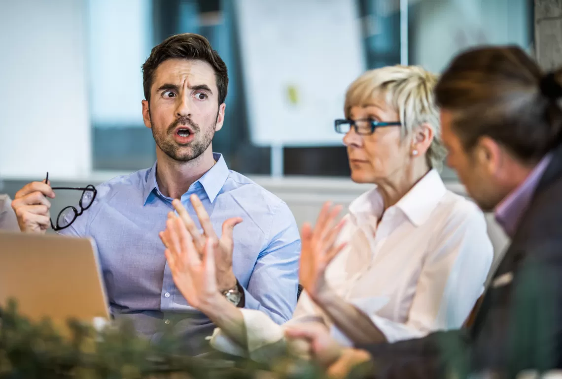 Three adults talking around a table in a work environment