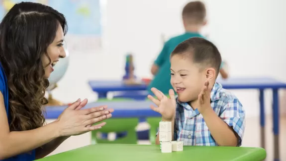 Teacher and young student clapping in a classroom 