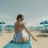 A woman sitting on the beach applying sunscreen 