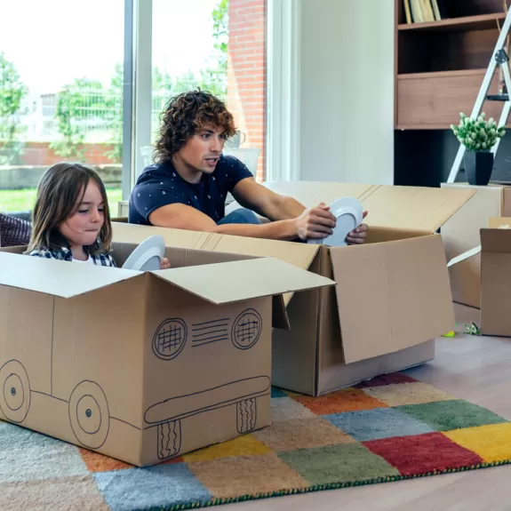 An adult and a child playing pretend in cardboard boxes